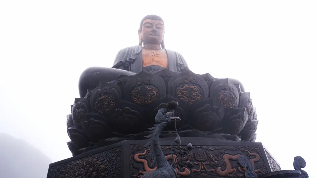 Gran estatua de Buda Amitabha sobre un pedestal decorado, envuelta en la niebla en la cima de Fansipan, en el norte de Vietnam