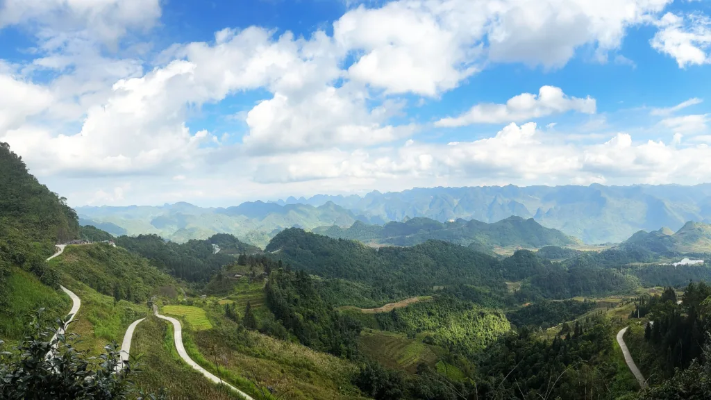 Panorámica Heaven's gate en Ha Giang con una carretera serpenteante entre valles verdes y montañas al fondo, en el norte de Vietnam